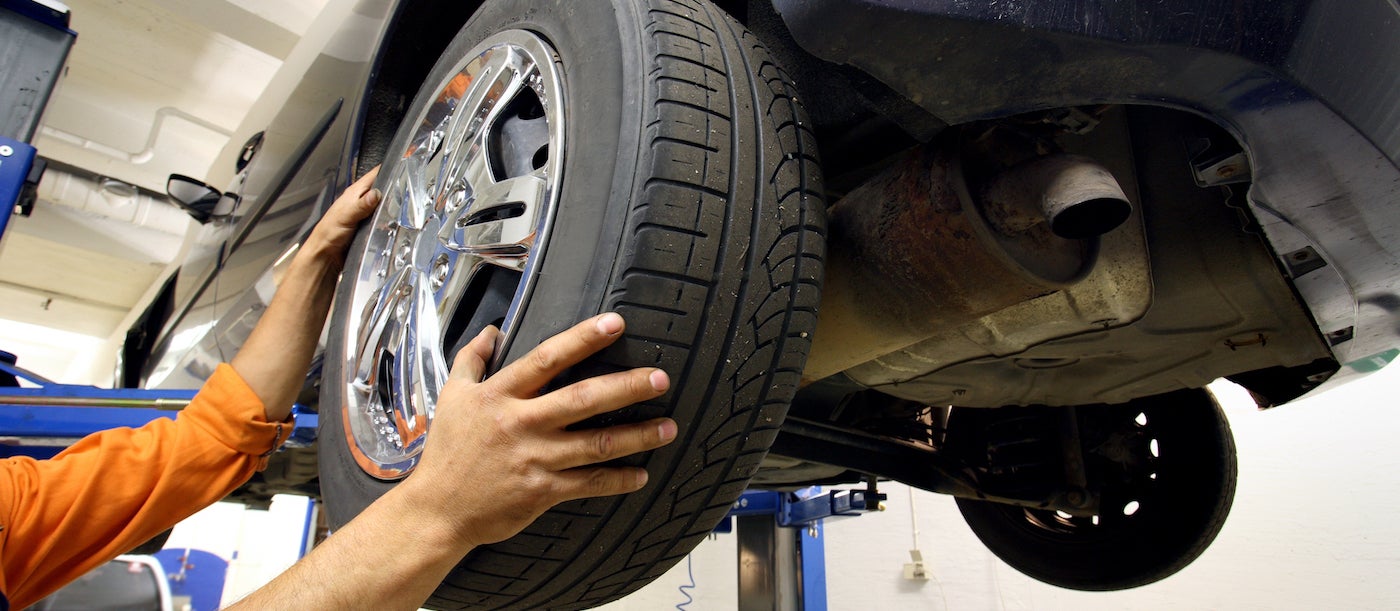 An auto mechanic rotating car tires.