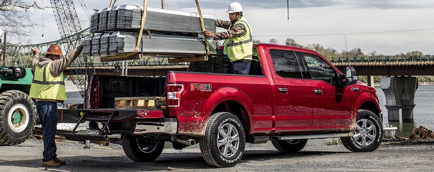 Workers loading steel into the bed of a 2020 Ford F-150
